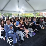 Ceremony attendees clap under a tent