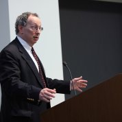 Baden gestures as he speaks at a lectern.