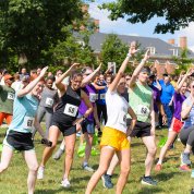 A large group of runners stretch on a grassy lawn.
