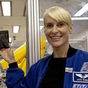 A smiling Rubins holds a dark gray, rectangular object with faint white markings.