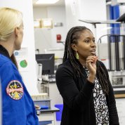 Rubins listens to a woman speaking in a lab.