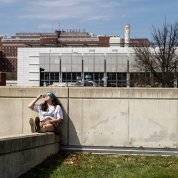 An observer sits on a ledge and looks up at the sky