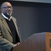 Gibbons, standing, speaks at a podium.