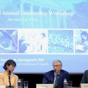 Bertagnolli (left), Gates (center), and Mundel (right) converse at a low table. A powerpoint presentation behind them announces the Gates-NIH Annual Leadership Workshop.