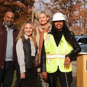Four ceremony attendees pose for a photo next to the podium.