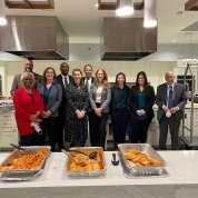 The servers stand proudly behind half-empty platters of food.