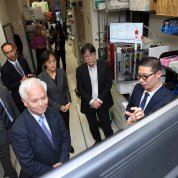 The delegation stands in a circle in a lab. 