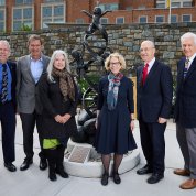 Six individuals pose for a photo in front of the statue.