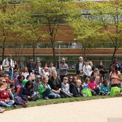 A large group of kids and parents assemble behind Bldg. 31 to watch canine demo with handler.