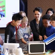 Kids look inside box at model of airways as child at left blows into tube and looks at a graph of her breathing.