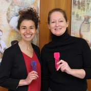Two smiling colleagues show off 3D-printed, scientific-themed bookmarks.