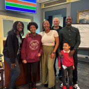 A group poses together with trivia categories highlighted in different colors above them.