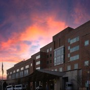 Pink and purple poke from the clouds above the facade of the Clinical Center
