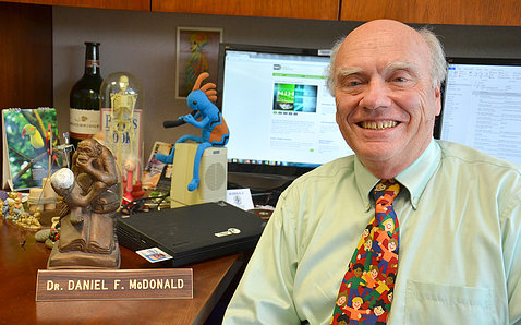 Dr. Daniel McDonald smiles sitting at his office desk.