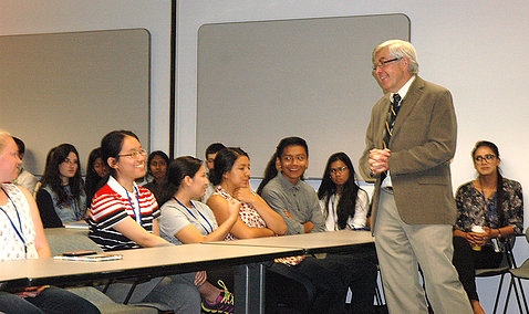 Standing, Koroshetz addresses students seated in classroom setting.