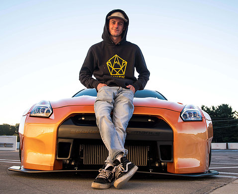 Andrew Lee poses in front of his bright orange Nissan GTR