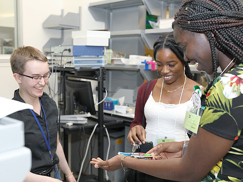 Girls in lab hold scientific equipment.