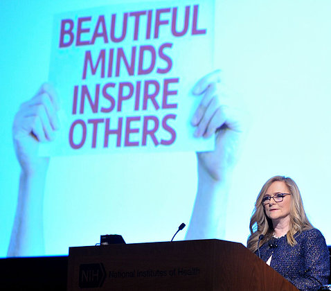 Dr. Guise speaks at podium in front of a slide that reads beautiful minds inspire others