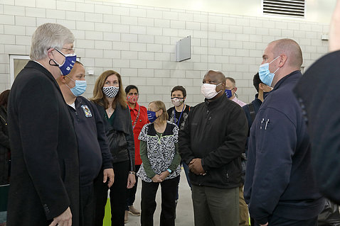 Collins greets several other employees standing in a semi-circle, with masks on.