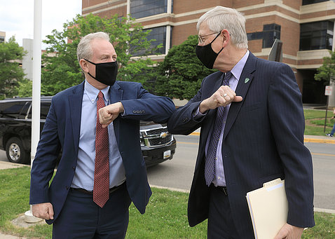 Collins and Sen. Van Hollen, wearing black masks, bump elbows standing outside the Vaccine Research Center.