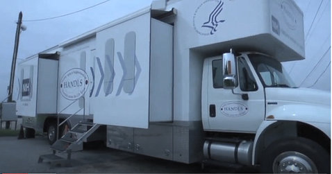 A large white truck with the NIH and HHS logos is a mobile medical research vehicle.