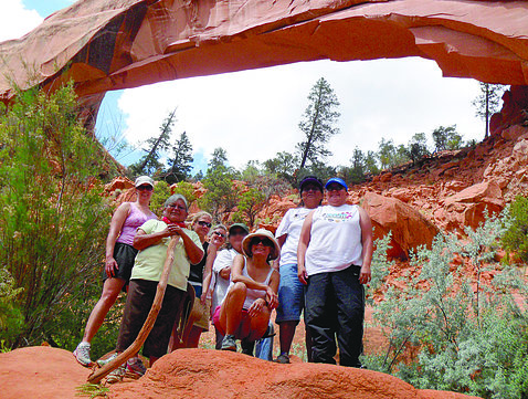 A group of people stand, surrounded by reddish rock formations.
