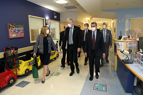 Collins and others walk along a corridor decorated for children and families.