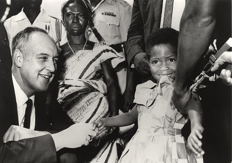 Black-and-white photo of surgeon general William Stewart holding a young Black girl's hand as a nurse holds an inoculation gun to the girl's other arm.