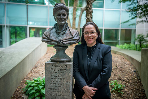 Quiroz stands in Clinical Center garden next to bust of Florence Mahoney.