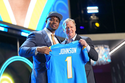Johnson and NFL commissioner hold up jersey with name on it.