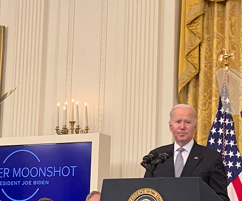 President Joe Biden at a White House East Room podium.