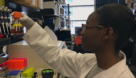 Side view of a research fellow holding a flask in the lab