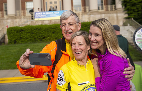 In front of Bldg. 1, Collins, in bike-riding gear, takes a selfie with wife Diane Baker and daughter Margaret