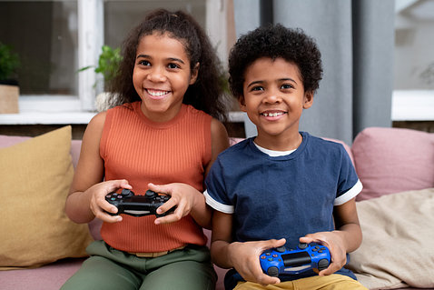 Two smiling children hold game consoles.