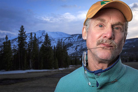 Quammen, with earpiece of eyeglasses in his mouth, poses in Yellowstone.
