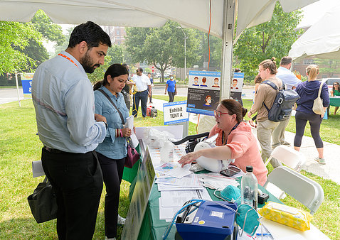 Staff stop at an information table under a tent at the fair.