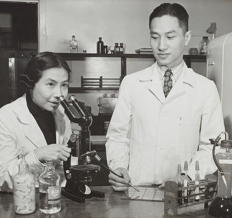 A black-and-white photo shows Wong peering over a microscope in the lab as Chien-lung looks on.