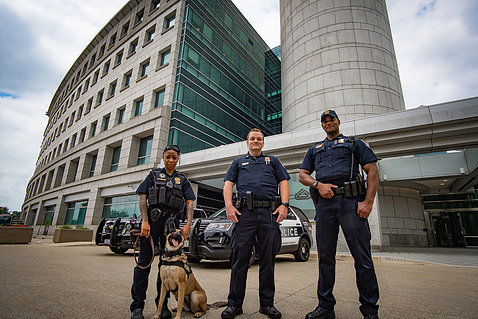 Three uniformed officers stand with a K9 dog in front of the Gateway Visitor Center