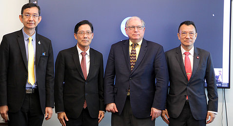 The four men stand in front of a blue background