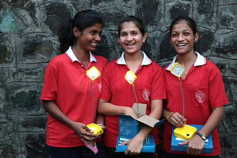 Three female students smiling together, wearing red and white shirts