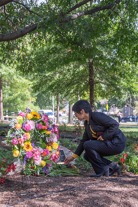 A visitor lays a flower on the plaque