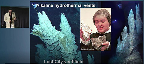 Small image of Lane speaking next to a powerpoint slide of spiky underwater hydrothermal vents.