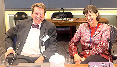 seated at conference table, Califf and Bertagnolli smile into camera