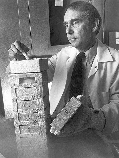 Black and white photo of McFarland lifting a small test tube from a box.