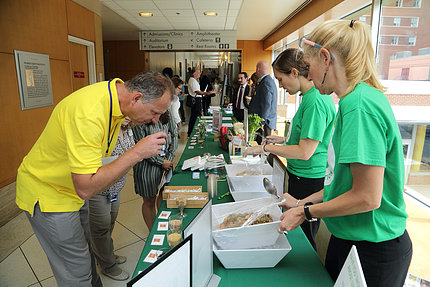 A couple of people lean over a table to examine food offerings.