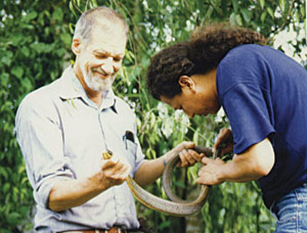 Daly holds snake in jungle.