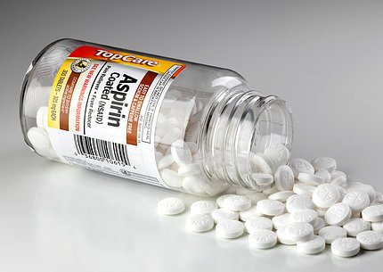 An opened bottle of aspirin lying on its side with tablets spilling out.