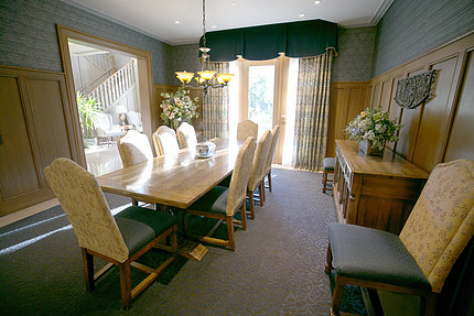 View of room from corner showing large rectangular table, 8 chairs with floor-to-ceiling window in background