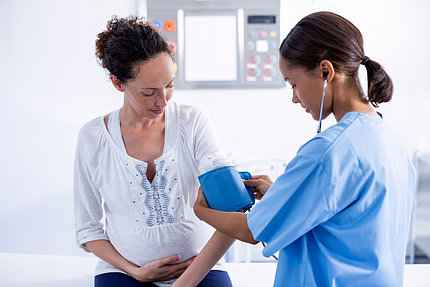 Nurse checks woman's blood pressure.