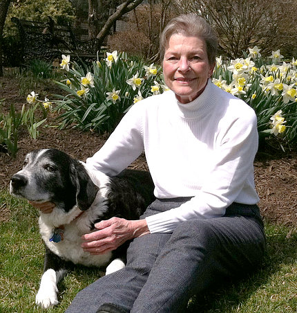 Hagan sits with her dog in front of a flower bed